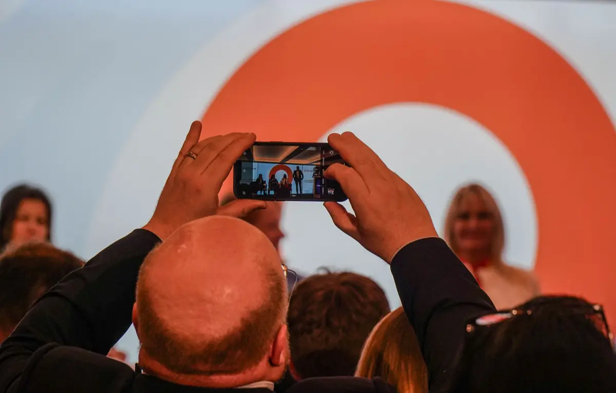 Delegates photographing a speaker on stage at an Inspired Summit